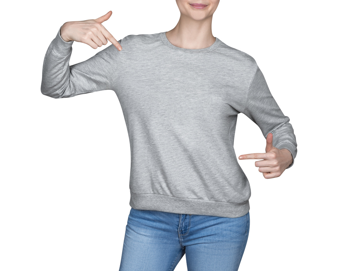 young girl in gray sweatshirt shows thumbs up. white background